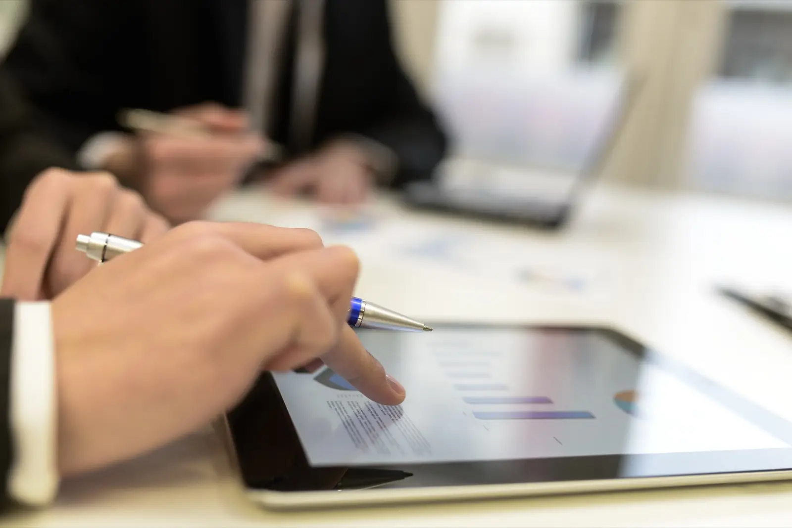Hands pointing at a chart on a tablet during a working meeting